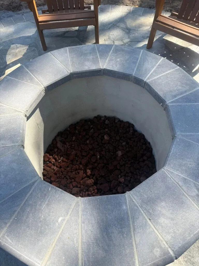 Stone fire pit installation with surrounding landscape design